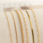 Six Essential Bracelet Chains, each with a polished finish and unique style, are displayed side by side on a soft, light surface with labeled names.
