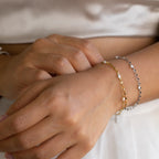 Detailed shot of model wearing gold and silver dainty pearl wrap bracelet to highlight difference in tones on warm skin tone. 