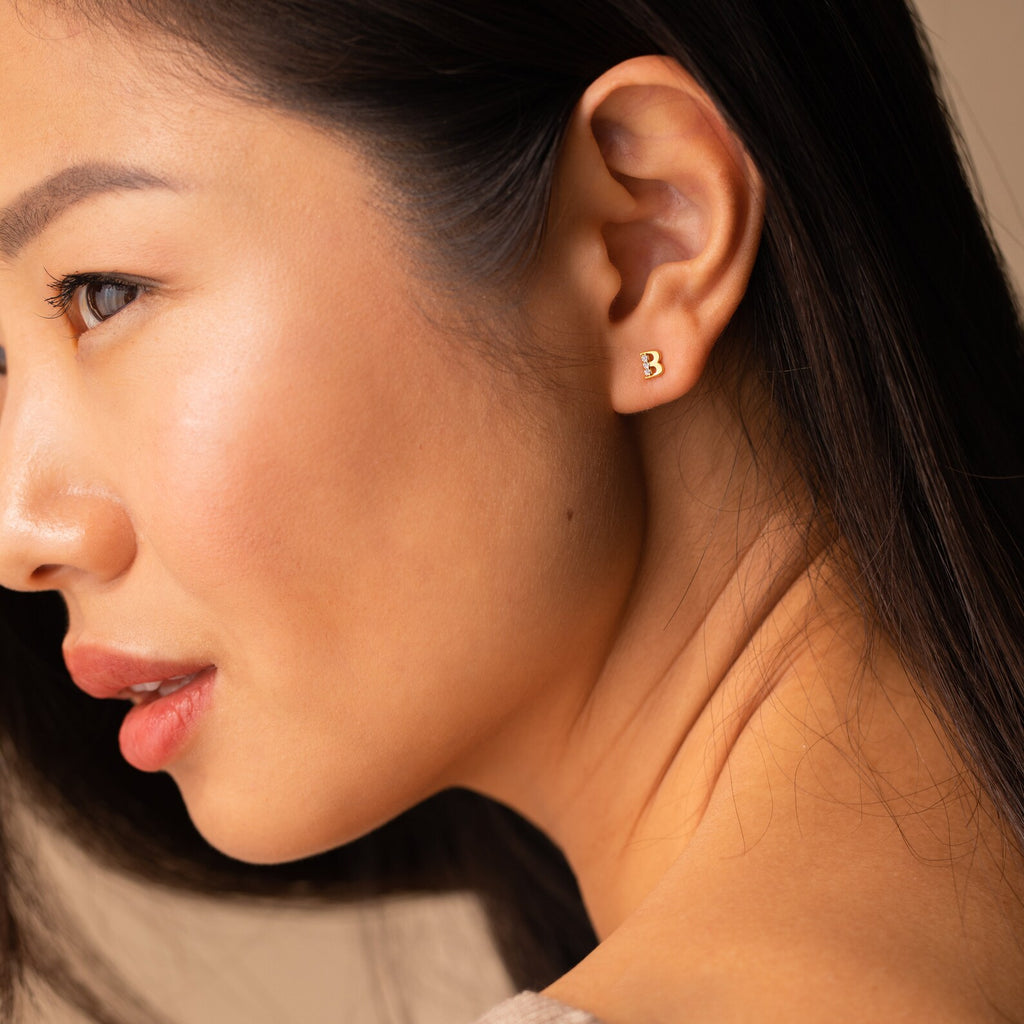 A close-up of a woman's face highlights her Pave Initial Studs, making them a truly personalized gift.