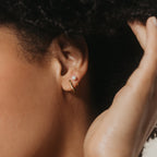 A close-up of a person's ear wearing a pearl stud and a minimal accessory: the contemporary Kelsey Link Earrings in gold.