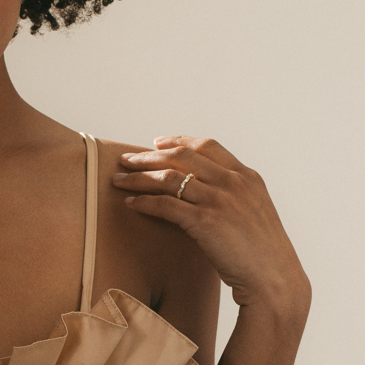 A hand wearing the Verity Diamond Ring with a gold cluster-style band rests near the shoulder of a person in a beige ruffled top.