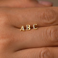 A hand with a gold letter studded ring, perfect as a personalized gift or paired with Pave Initial Studs.
