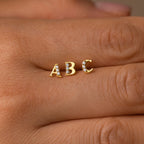 A hand with a gold letter studded ring, perfect as a personalized gift or paired with Pave Initial Studs.
