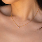 Close-up of a woman wearing the Dainty Birthstone Necklace—a delicate gold chain with a small gemstone pendant, perfect as meaningful jewelry or an elegant birthstone accessory.