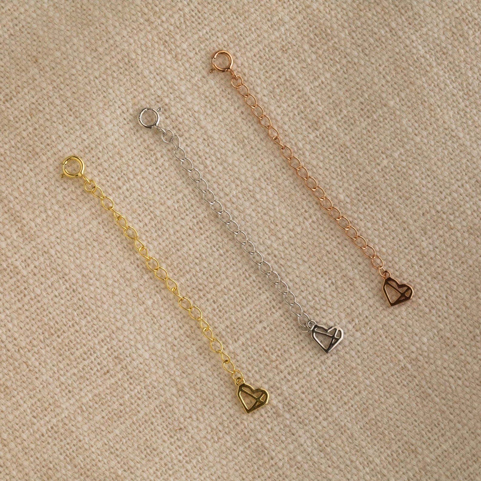 The Chain Extender in Sterling Silver is displayed on a beige fabric background—perfect to personalize jewelry or adjust necklaces and bracelets for the ideal fit.