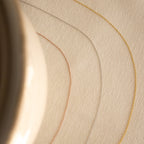 The Dainty Chain Necklace, shown in gold, silver, and rose gold, curves across a beige textured surface with a blurred object to the left for a refined minimal look.