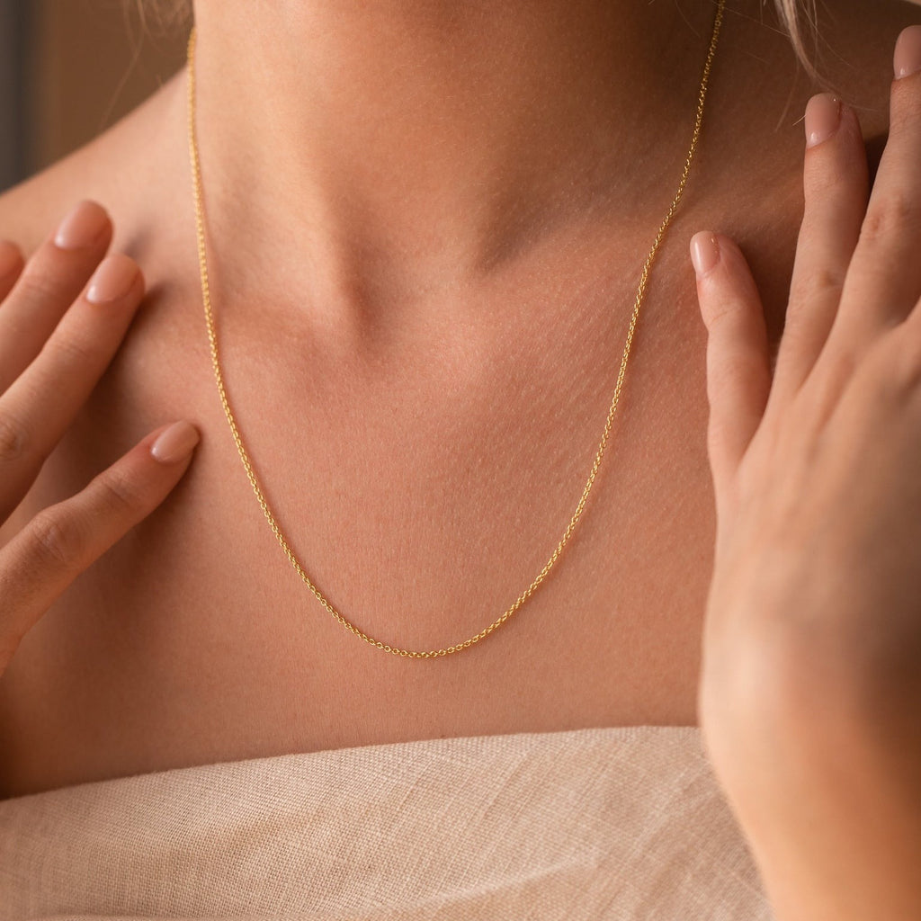 A woman models the Dainty Chain Necklace, her hands near her collarbone and dressed in a beige top for a minimalist look.