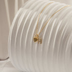 Pave Initial Heart Necklace featuring a gold heart charm and initial pendant with rectangular accents, elegantly displayed on a textured white surface.