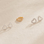 A row of heart-shaped earrings, the Clarissa Pave Huggies, and a pair of gold earrings—perfect additions to your date night jewelry collection.