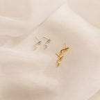 Two pairs of Opal Ear Jackets—one silver, one gold—displayed on soft white fabric. Each features removable earring posts for versatile styling.