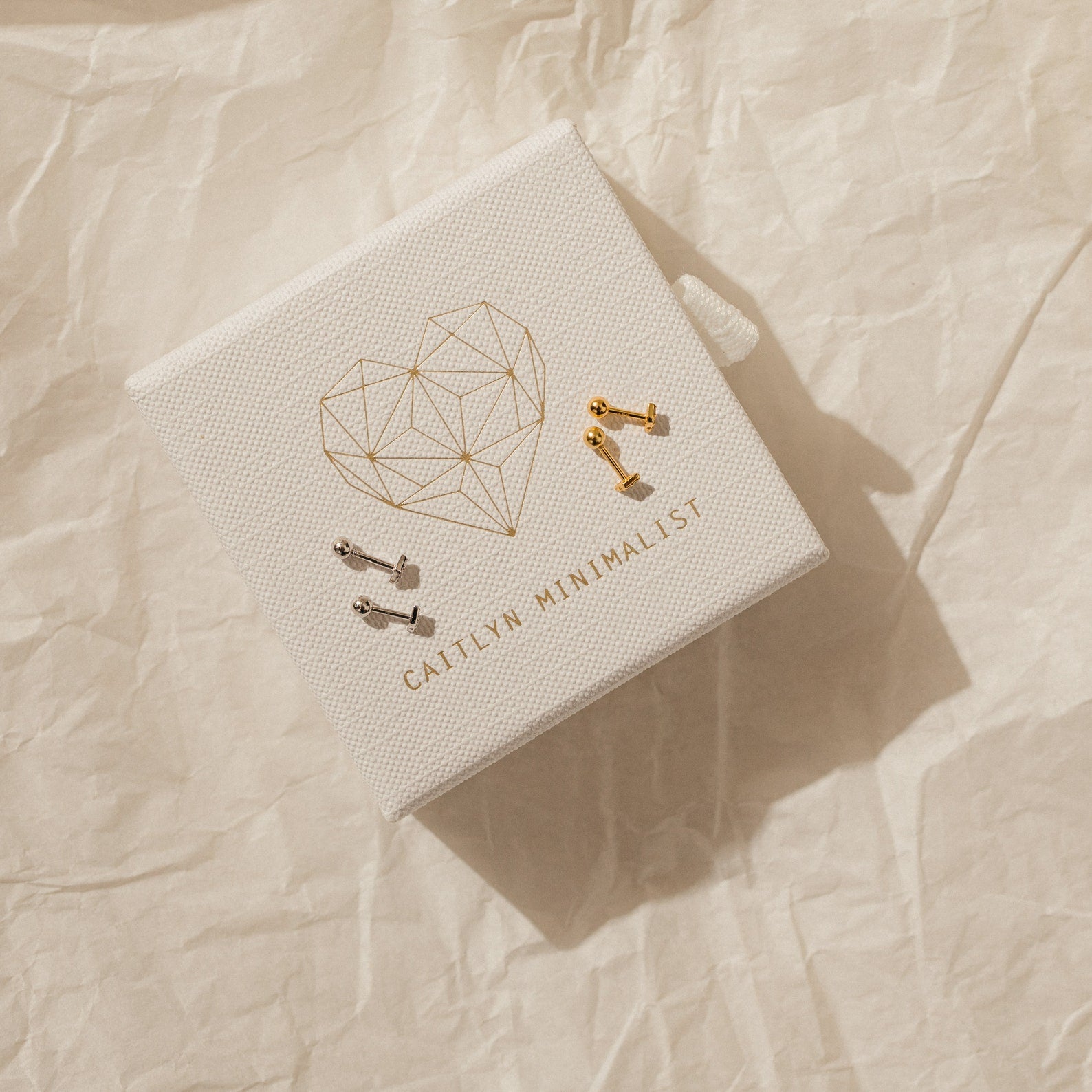 A pair of Jocelyn Diamond Studs in 18K Gold features a minimalist design and ball back, presented on a textured box embossed with GALLIV MINIMALIST.