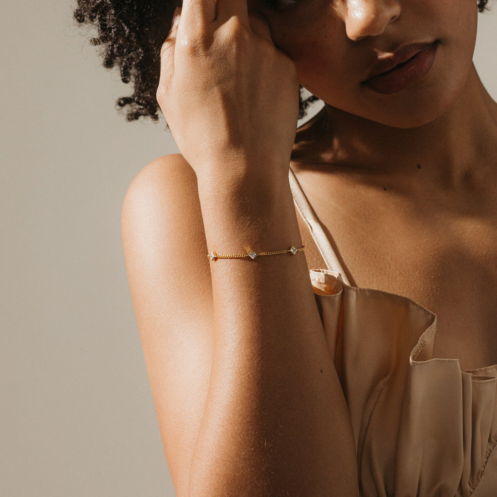 A woman wearing the Venus Diamond Station Bracelet and a beige satin dress, her hand near her face—an elegant choice for wedding jewelry or an unforgettable anniversary gift.