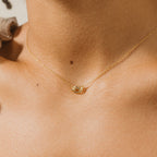 Close-up of a person wearing the Love Knot Necklace, featuring a gold chain with a small knot pendant—ideal as unity jewelry or a meaningful wedding gift.