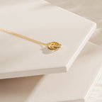 Engraved Interlocking Necklace featuring personalized names, shown on white ceramic tiles—an elegant anniversary gift.