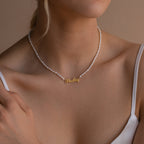 Woman wearing the Mellow Pearl Name Necklace, featuring a gold Hailey name pendant and pearls, styled with a white spaghetti strap top.