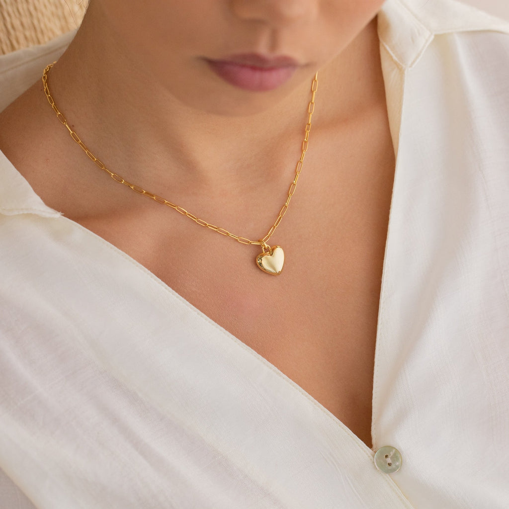 Woman wearing a white blouse and the Taylor Heart Paperclip Necklace, a minimalist gold heart locket.