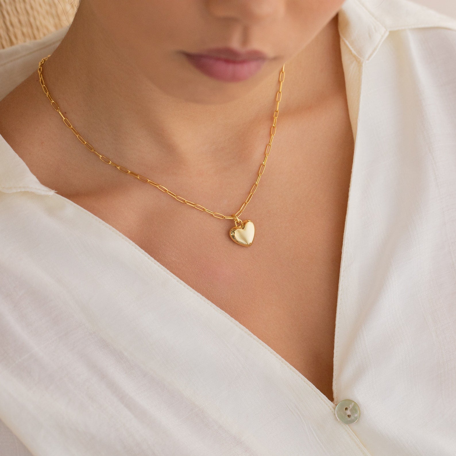 Woman wearing a white blouse and the Taylor Heart Paperclip Necklace, a minimalist gold heart locket.