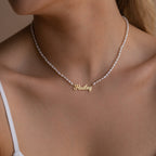 A woman wears the Mellow Pearl Name Necklace, which features a gold pendant with the name Hailey.
