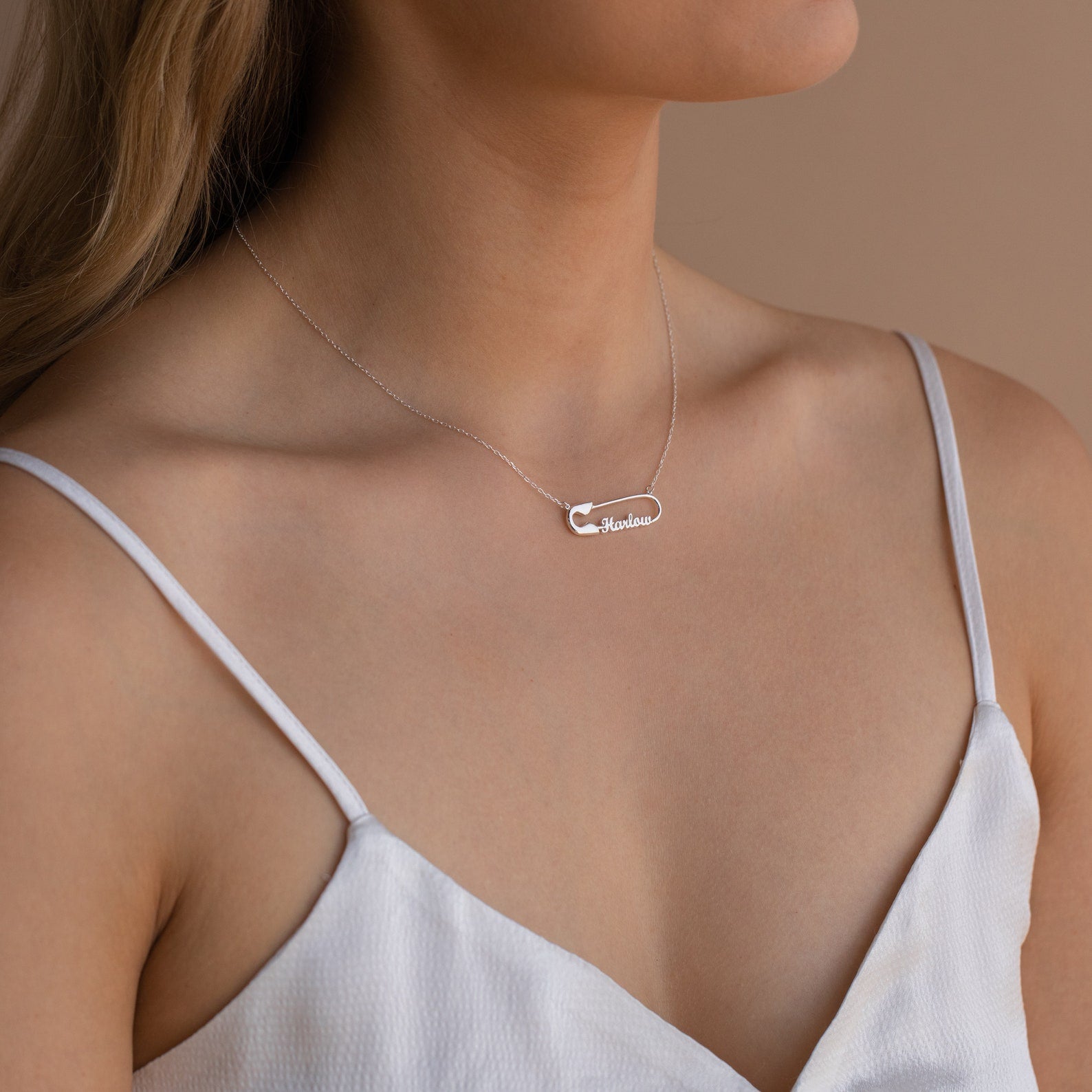 Woman wearing a white spaghetti strap top and a delicate silver Safety Pin Name Necklace with a personalized pendant.