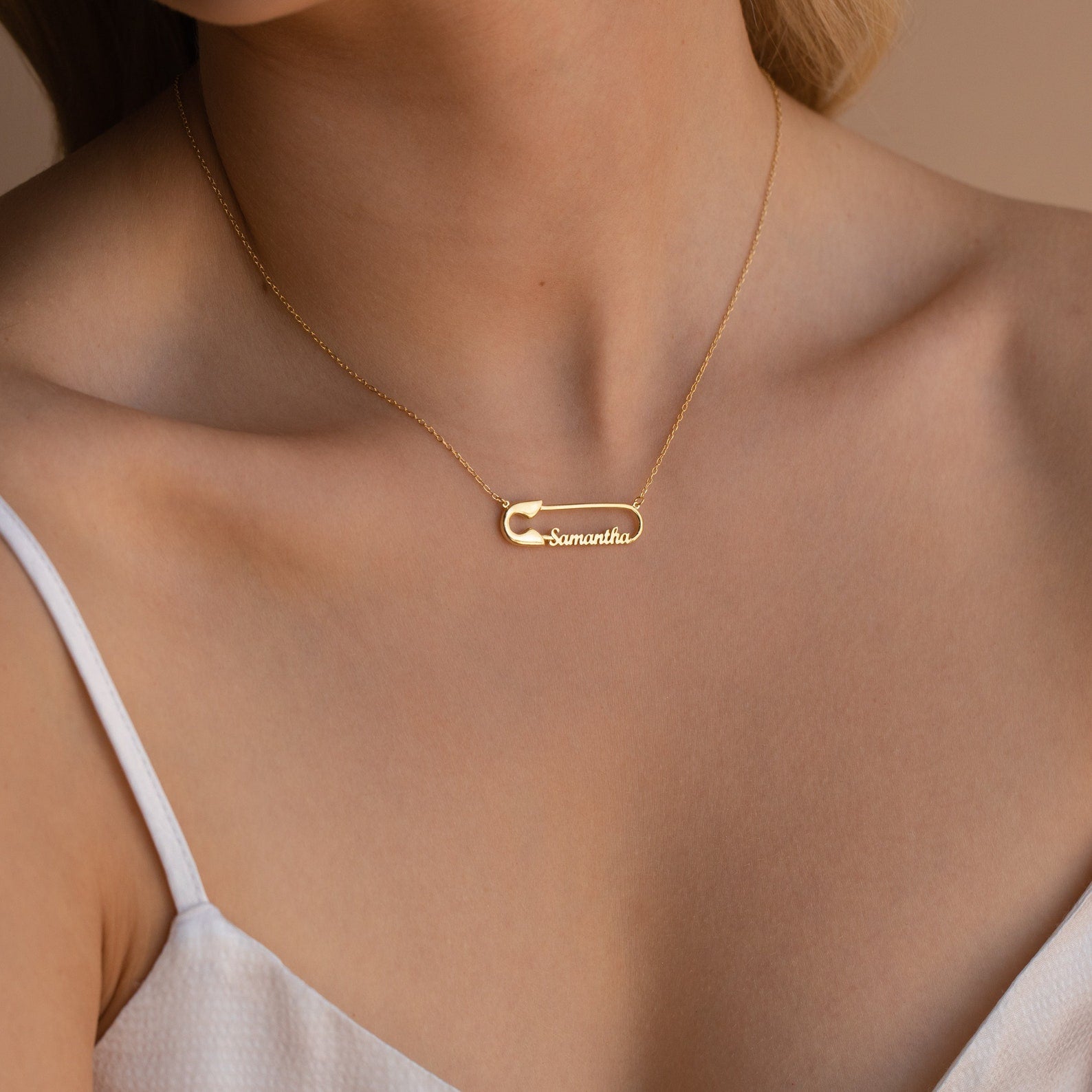 Safety Pin Name Necklace featuring the name "Samantha," worn by a woman in a white top—a personalized gold accessory that's the perfect statement piece.