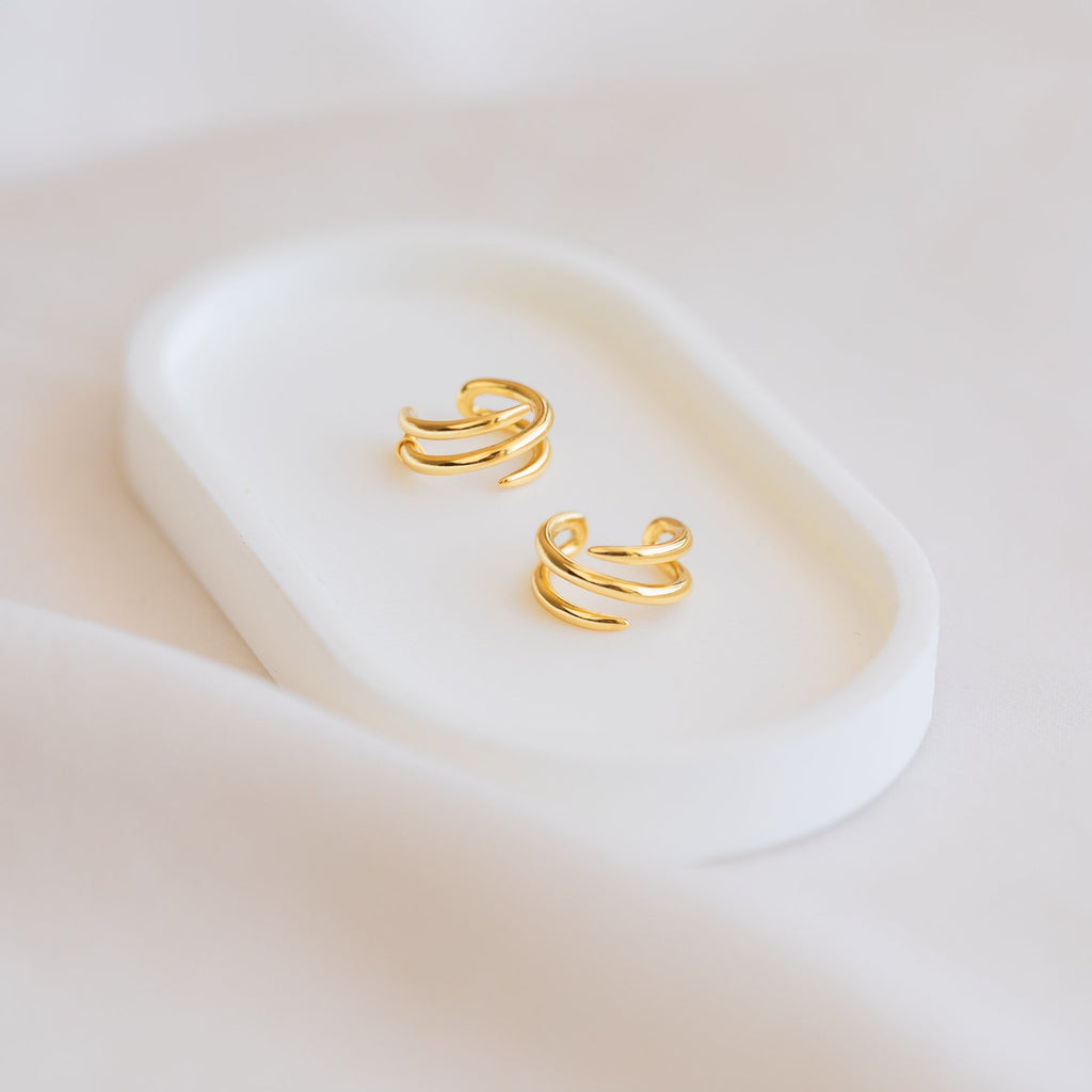 Claw Ear Cuffs with a delicate double-band design rest on a white oval tray against a soft, light background—ideal for fans of dainty earrings.