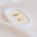 Claw Ear Cuffs with a delicate double-band design rest on a white oval tray against a soft, light background—ideal for fans of dainty earrings.