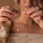 Hands holding two delicate gold chain earrings with small heart-shaped pendants, perfect for pairing with the Chain Extender in Rose Gold for an adjustable fit.