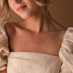 A woman in an off-shoulder beige top wears the Dainty Chain Necklace, with soft lighting highlighting her minimal style.