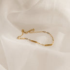 Mini Name Bar Bracelet featuring three personalized bar nameplates—AMELIA, SOPHIE, and EMMA—on a gold paperclip chain, displayed on a white fabric background; a perfect custom gift for someone special.