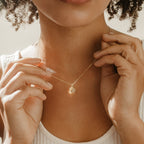 A woman wearing a white ribbed top showcases the Pave Initial Heart Necklace.