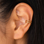 Close-up of an ear wearing double gold Claw Ear Cuffs on the cartilage, paired with straight dark hair—a chic, elegant style for fans of dainty earrings.