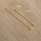 Two Chain Extender gold adjustable chains with heart charms, sized 3" and 2", are displayed on beige fabric—ideal for lengthening your favorite necklaces or bracelets.