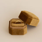 Single slot velvet ring box in caramel brown with gold ring displayed on beige neutral background