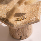 A pair of Seine Diamond Studs rests elegantly on a stone pedestal—perfect as timeless wedding earrings.