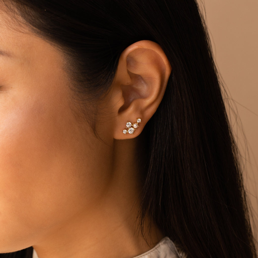 Woman with long dark hair wears a cluster of three Seine Diamond Studs with diamond accents on her earlobe.