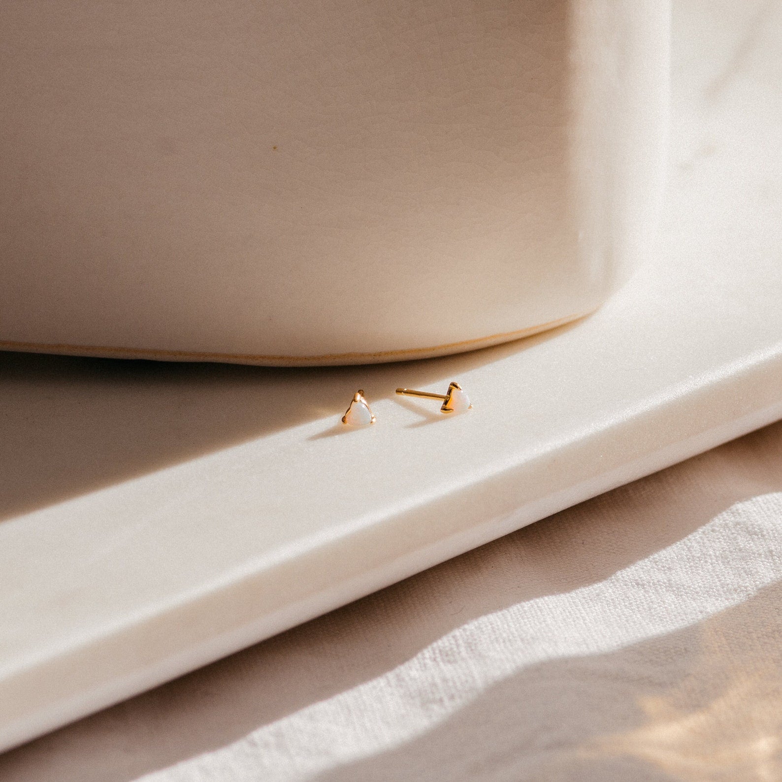 Two Opal Heart Studs are displayed on a sunlit white marble surface, casting soft shadows—ideal for adding minimal glam to your dainty earring collection.
