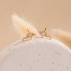 The Starry Night Ear Cuffs are gold, star-shaped cuffs with small crystals, elegantly displayed on a textured white stone and soft beige background. These no-piercing earrings add a sparkling touch to any look.