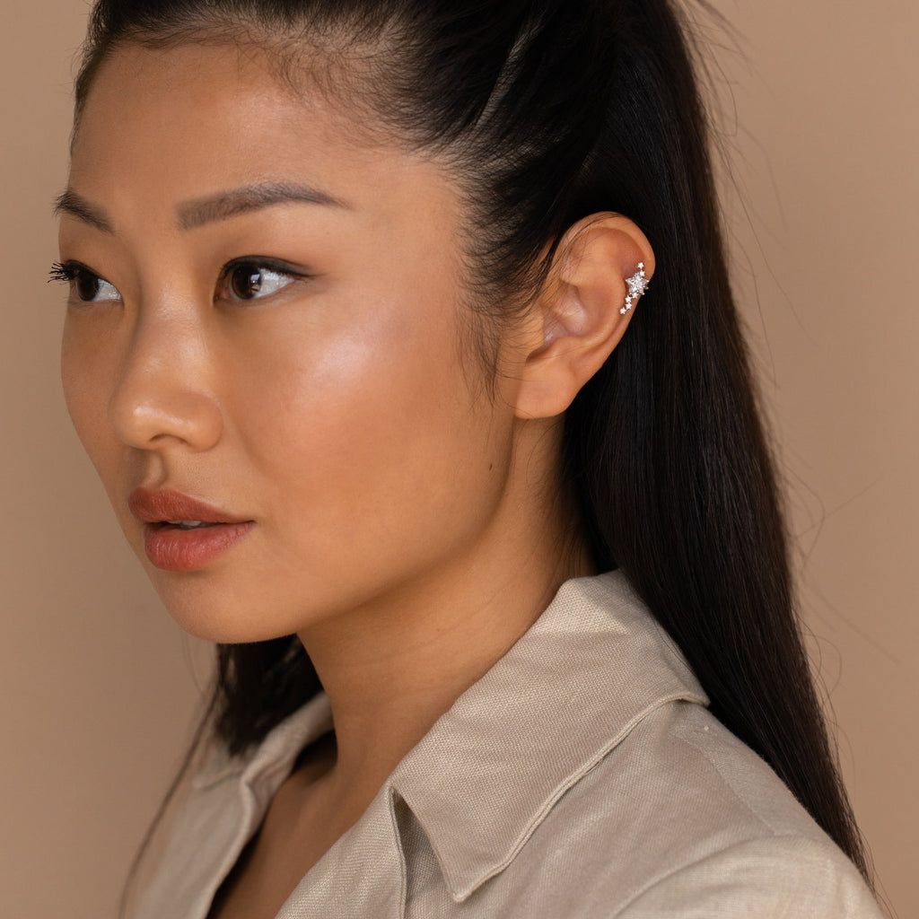 A woman with long dark hair wearing a beige shirt and the Starry Night Ear Cuffs, ideal for anyone who loves cuff earrings without needing a piercing, gazes to the left.