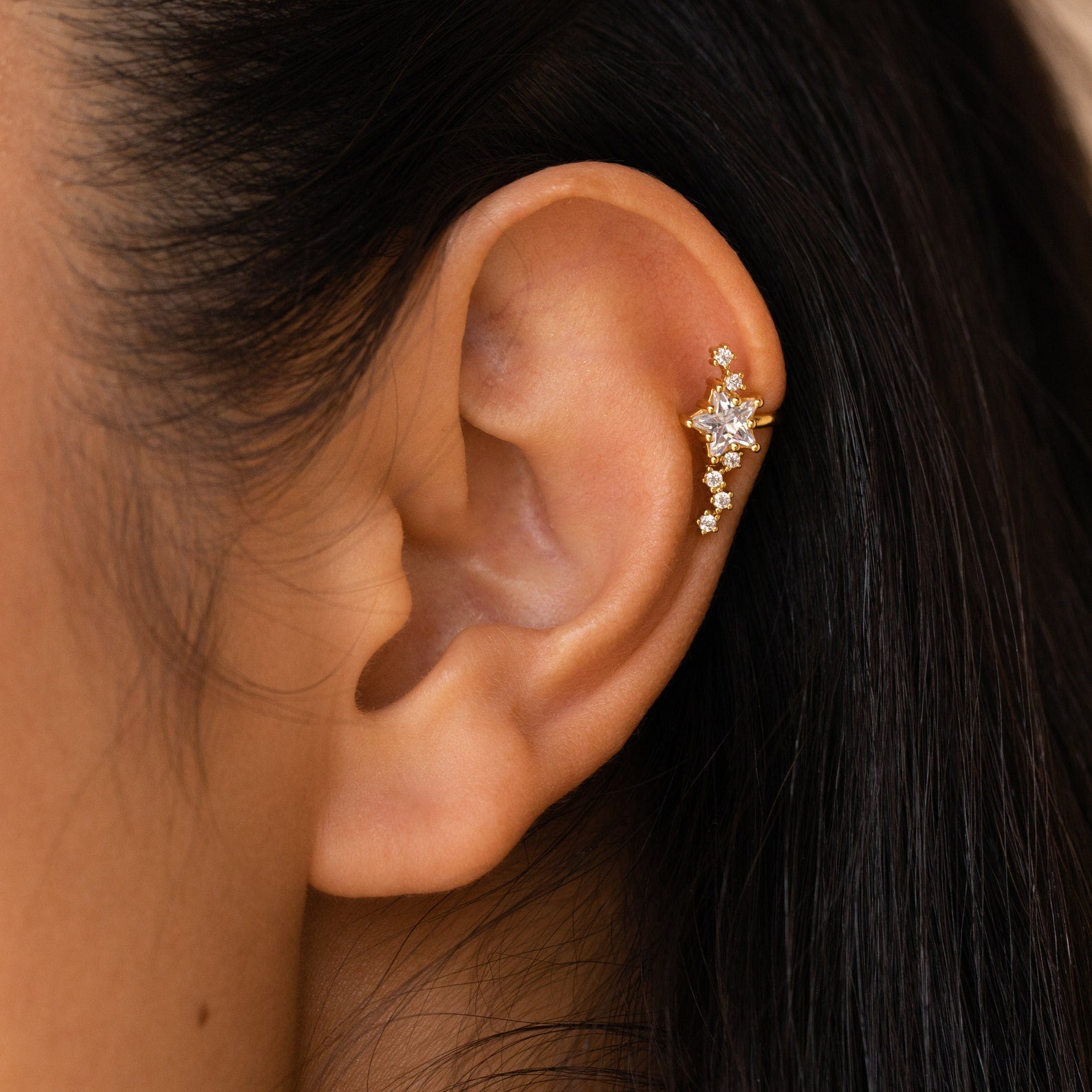 Close-up of an ear with Starry Night Ear Cuffs—gold, no-piercing cuff earrings adorned with star-shaped and round crystals for a stylish look.