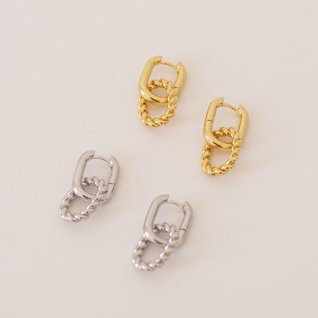 Two pairs of Kenzie Chain Link Earrings—one gold, one silver—with an edgy twisted design are displayed on a light surface.