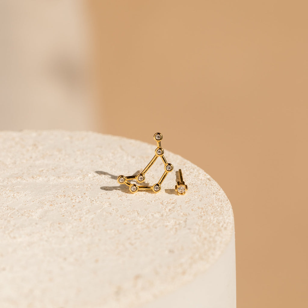 Constellation Earrings with small stones, displayed on a textured beige surface and minimalist background—ideal for fans of astrology-inspired style.