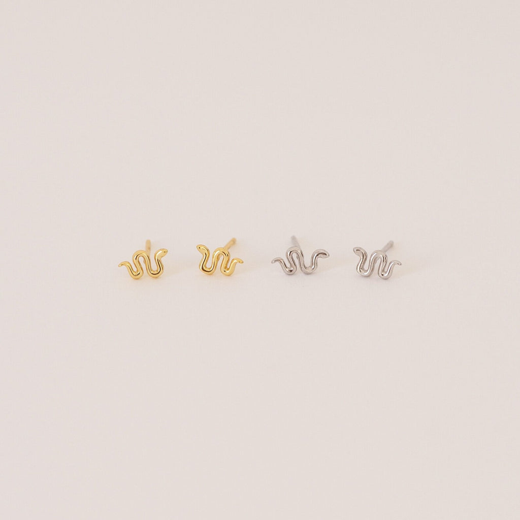 The Tiny Python Studs feature a chic snake design in gold and silver, adding subtle edge to your style. Perfect for boho-luxe earring lovers, these dainty studs are set against a light, neutral backdrop.