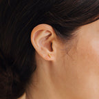 Close-up of a woman's ear wearing Trio Beaded Bar Studs in gold—minimalist earrings perfect for everyday style.