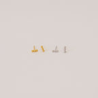 Two pairs of Trio Beaded Bar Studs—one gold, one silver—each featuring three round beads. These minimalist earrings are perfect for everyday wear and are shown against a plain background.