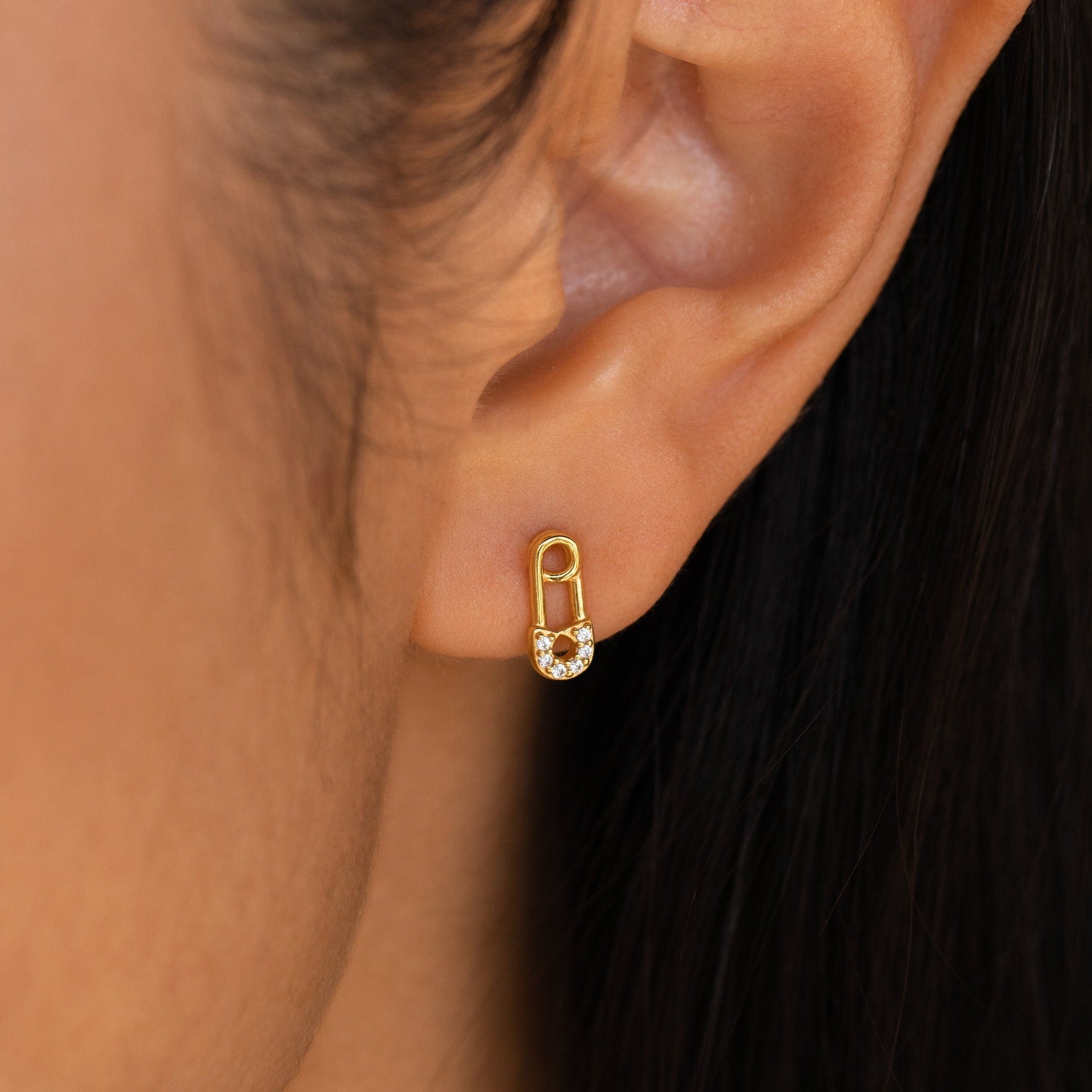 Tiny Pave Safety Pin Studs featuring a small CZ diamond sit elegantly on the ear.
