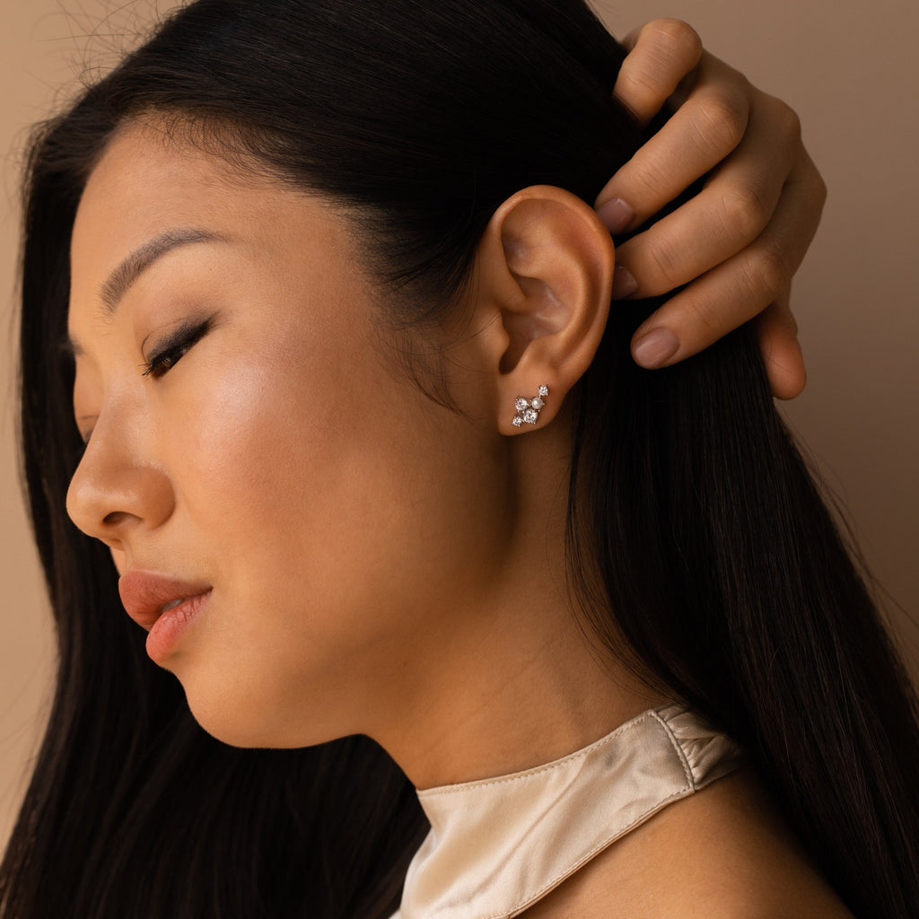 Woman with long dark hair wearing a cream top and Seine Diamond Studs, featuring cultured pearls, touches her hair behind her ear.