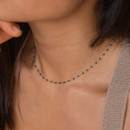 Close-up of a woman wearing the Emerald Station Necklace, adorned with small emerald green beads and shimmering silver accents.