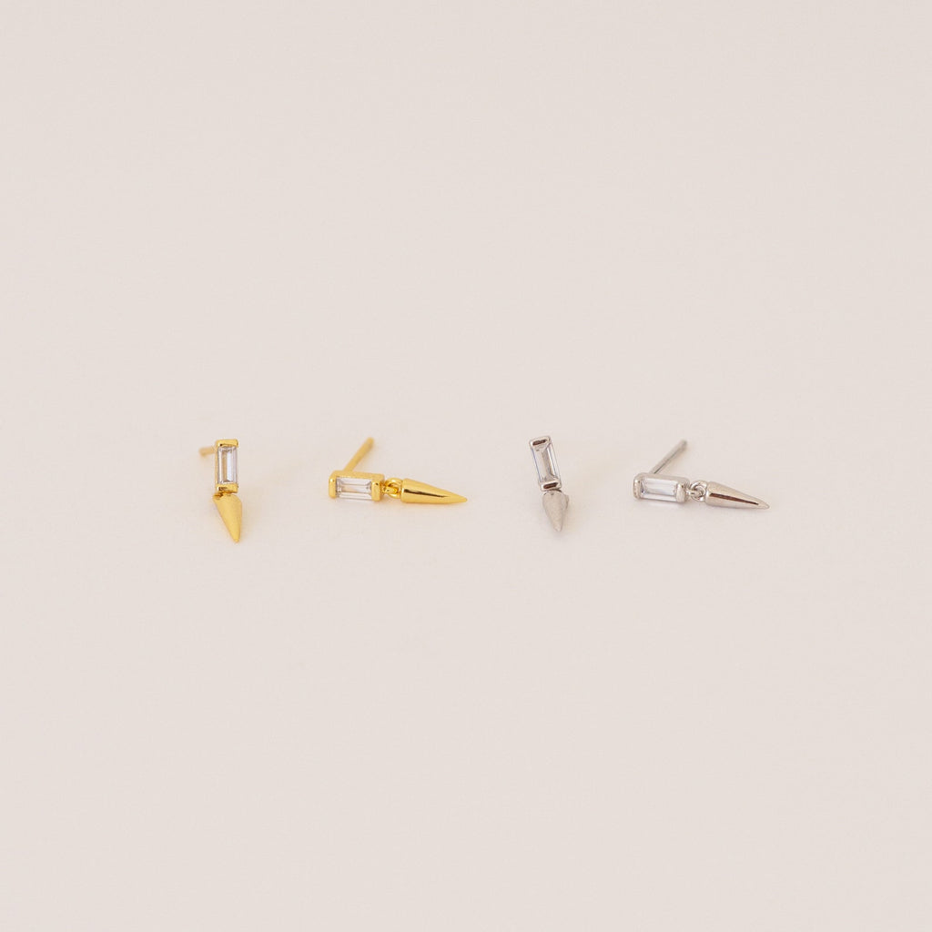 Two pairs of Wren Spike Studs, one gold and one silver, each with a spike-shaped design and lightweight feel, displayed on a light background.