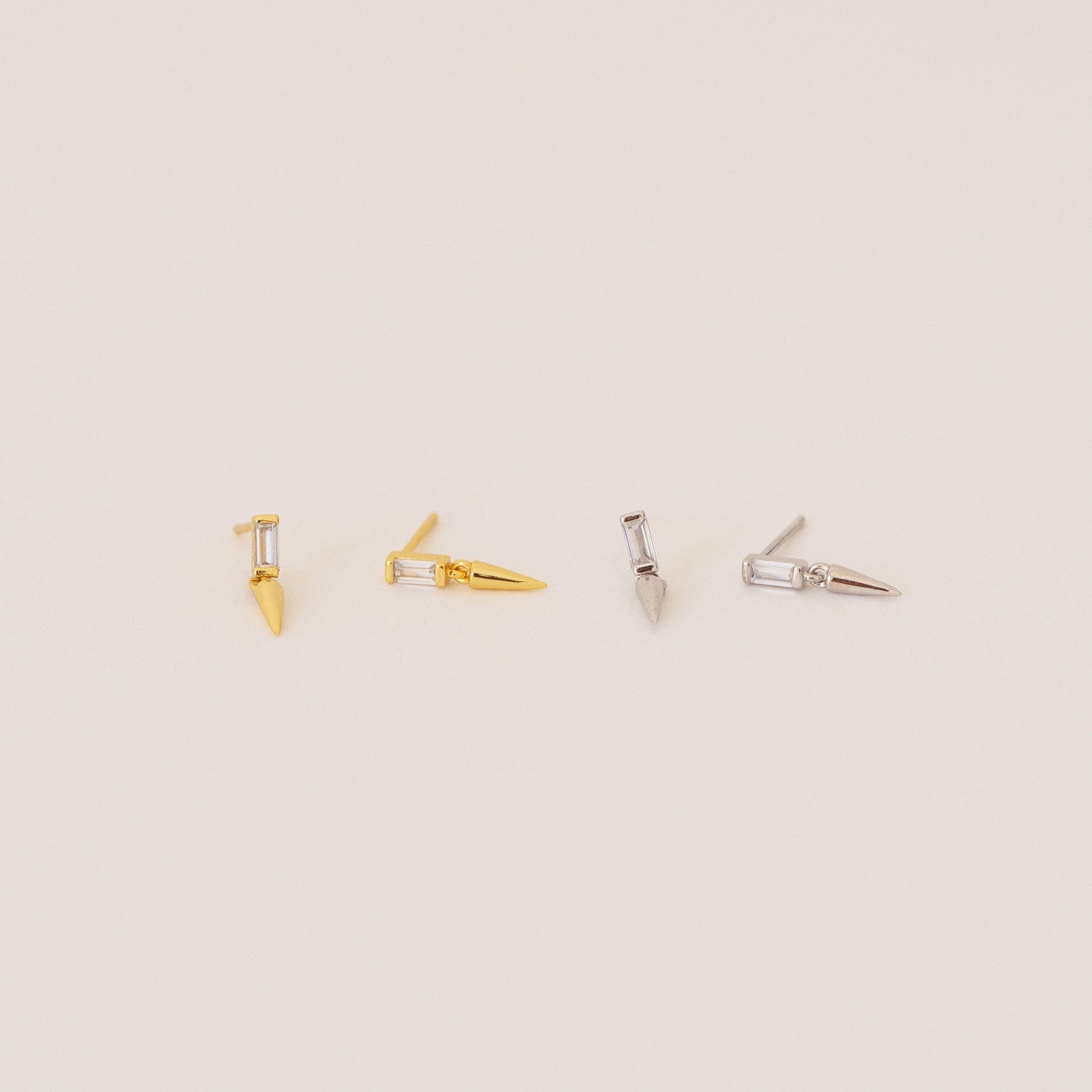 Two pairs of Wren Spike Studs, one gold and one silver, each with a spike-shaped design and lightweight feel, displayed on a light background.