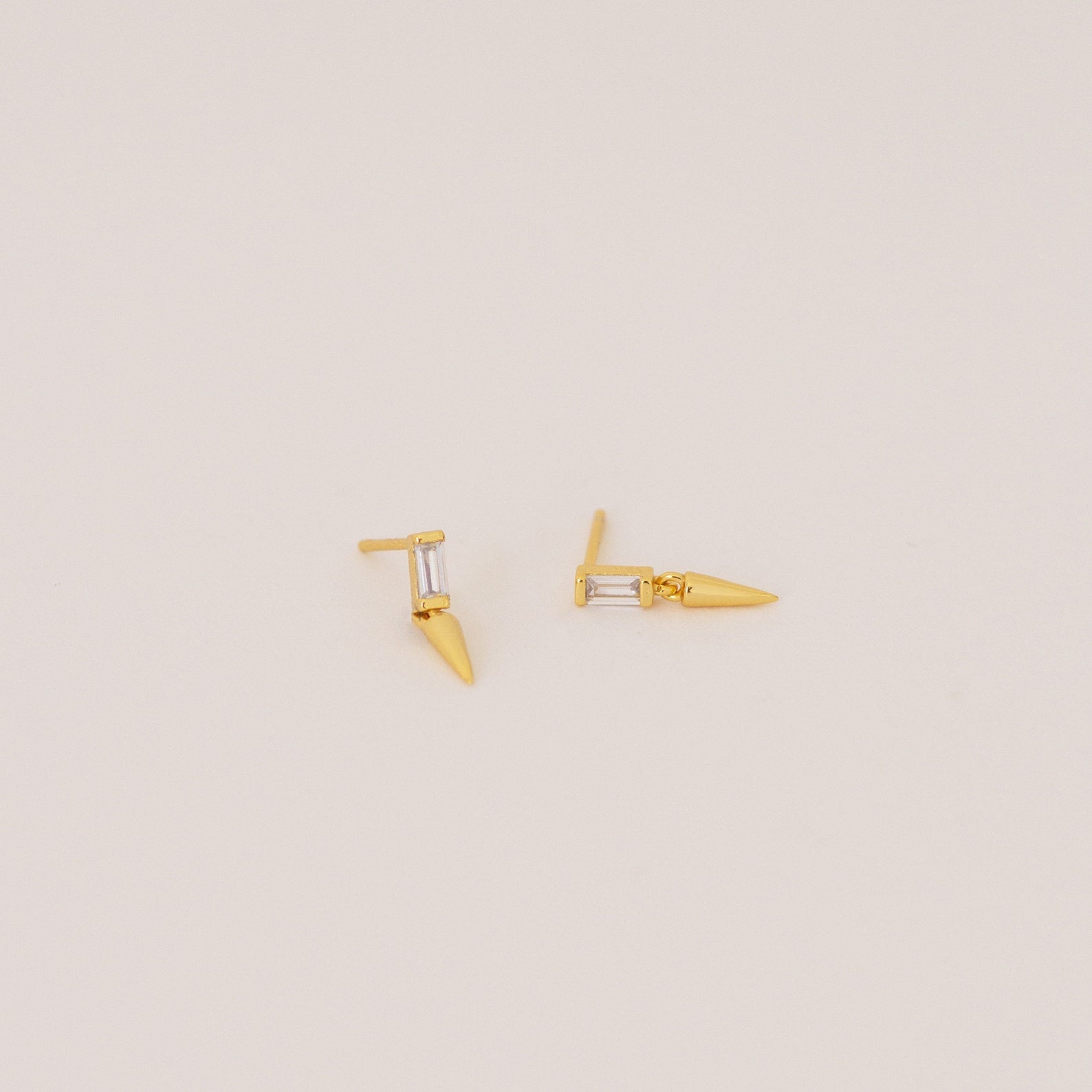 The Wren Spike Studs are lightweight, small spike-shaped earrings featuring CZ baguette diamonds and a pointed spike detail, set against a plain background.